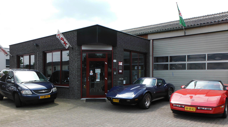 ATC-Autoservice aan de Rozenobel in Beringe, met een blauwe en een rode Corvette en een Chrysler Voyager voor de deur